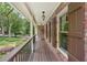 Inviting covered front porch with brick accents, wood flooring, and classic railing showcasing outdoor living space at 10875 Shagbark Trl, Roswell, GA 30075