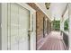Charming front porch featuring brick accents, wooden flooring, and a white front door with glass detailing at 10875 Shagbark Trl, Roswell, GA 30075