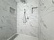 Modern shower featuring white marble-patterned tile, rainfall showerhead, handheld sprayer, and recessed shampoo niches at 10875 Shagbark Trl, Roswell, GA 30075