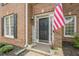 Close-up of front door with sidelights, a patriotic flag, potted plants, and a welcome sign, creating an inviting entry at 1245 Mountain Ivey Ct, Sugar Hill, GA 30518