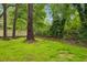Lush backyard with green grass, mature trees, and a wooden fence, creating a serene outdoor space at 2760 Fraser Se St, Smyrna, GA 30080