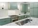 Close up of modern kitchen with marble countertops, stainless steel appliances and sink, and green cabinets at 2760 Fraser Se St, Smyrna, GA 30080