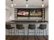 Stylish basement bar featuring four bar stools, a sleek countertop, and two large TVs for entertainment at 3834 Chamblee Dunwoody Rd, Atlanta, GA 30341