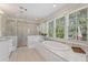 Bright bathroom with marble shower, soaking tub under windows, and marble countertops at 3834 Chamblee Dunwoody Rd, Atlanta, GA 30341
