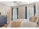 Well-lit bedroom features stylish decor, including a padded headboard, wood floors, and elegant blue curtains at 3834 Chamblee Dunwoody Rd, Atlanta, GA 30341