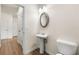 Cozy half bathroom featuring a pedestal sink, oval mirror, and modern lighting at 228 Whitneys Way, Dallas, GA 30157