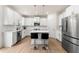 Bright kitchen with white cabinets, stainless steel appliances, island with seating, and hardwood floors at 228 Whitneys Way, Dallas, GA 30157