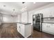 Open kitchen with white cabinets, stainless steel appliances, kitchen island, and hardwood floors flowing into the living area at 3524 Preserve Run Trl, Loganville, GA 30052