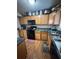 Kitchen with wood cabinets, black appliances, dark countertops, and light wood-look flooring at 6550 Wellington Chase Ct, Lithonia, GA 30058