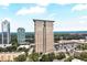 Aerial view of a tall, modern apartment building with tree top views, a parking area, and shopping close by at 2881 Peachtree Ne Rd # 1202, Atlanta, GA 30305