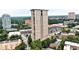 An aerial view of a high rise apartment building with tree top views, a parking area, and local businesses at 2881 Peachtree Ne Rd # 1202, Atlanta, GA 30305