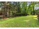 Expansive grassy backyard featuring mature trees, with a partial view of the home's exterior at 621 Windgrove Se Rd, Marietta, GA 30067