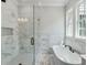 Bathroom featuring white marble tile, glass-enclosed shower, soaking tub, and a large window at 1294 Six Sisters St, Dacula, GA 30019