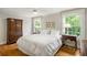 Light-filled bedroom with hardwood floors, white linens, and windows with a view of lush greenery at 380 Lamplighter Se Ln, Marietta, GA 30067