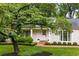 Inviting white home with green shutters and brick pathway, complemented by mature landscaping and a large tree at 380 Lamplighter Se Ln, Marietta, GA 30067