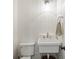 A small powder room includes a pedestal sink, toilet, tiled wall, and modern light fixture at 380 Lamplighter Se Ln, Marietta, GA 30067