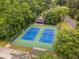 Aerial view of the community tennis courts with new, blue surfaces surrounded by trees at 1981 Sumter Ct, Lawrenceville, GA 30044