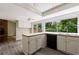 Bright kitchen features white cabinets, an island, stainless steel sink, and a large window with a view to trees at 135 Pheasant Se Dr, Marietta, GA 30067