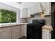 Updated kitchen showcases white cabinets, a black gas range, mosaic tile backsplash, and a stainless steel sink at 135 Pheasant Se Dr, Marietta, GA 30067