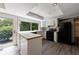 Bright kitchen featuring white cabinets, black appliances, and views of backyard from sliding glass doors at 135 Pheasant Se Dr, Marietta, GA 30067