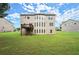 Spacious backyard featuring a deck, large lawn, and mature trees under a sky with bright clouds at 1709 Grove Se Ct, Conyers, GA 30013