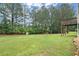 A spacious backyard with lush green grass, mature trees, and a view of the home's exterior and deck at 1709 Grove Se Ct, Conyers, GA 30013