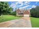 Beautiful brick home with a large driveway, manicured lawn, and mature trees at 1709 Grove Se Ct, Conyers, GA 30013