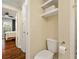 This bathroom features a standard white toilet, white floating shelving, and hardwood floors extending to the bedroom at 869 Briarcliff Ne Rd # B20, Atlanta, GA 30306