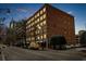 Exterior nighttime view of a red brick building with numerous windows, street parking and city skyline view at 800 Peachtree Ne St # 8607, Atlanta, GA 30308
