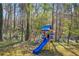 Backyard featuring a wooden playset for children, surrounded by mature trees and greenery at 10845 Shallowford Rd, Roswell, GA 30075