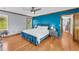 Primary bedroom with hardwood floors and a blue accent wall, featuring a comfortable bed at 10845 Shallowford Rd, Roswell, GA 30075
