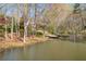Pond view featuring a dock, surrounded by trees creating a private and peaceful waterfront retreat at 10845 Shallowford Rd, Roswell, GA 30075