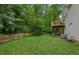 View of the spacious backyard featuring a deck and complemented by mature trees and a wooden fence at 5519 Princeton Oaks Ln, Sugar Hill, GA 30518