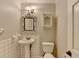 Charming half bathroom with ornate mirror, pedestal sink, and tiled wall at 10035 Anaheim Dr, Alpharetta, GA 30022