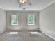 Bright bedroom featuring neutral walls, carpet, and a ceiling fan, illuminated by natural light from two windows at 10035 Anaheim Dr, Alpharetta, GA 30022