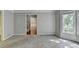 Neutral living room with plush carpeting, large windows, and a view into the hallway and staircase at 10035 Anaheim Dr, Alpharetta, GA 30022
