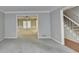 Spacious living room featuring neutral walls, plush carpeting, and a clear view to the home's staircase at 10035 Anaheim Dr, Alpharetta, GA 30022