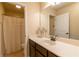 A well-lit bathroom with a vanity, large mirror, and shower with a neutral-colored curtain at 12275 Styron Dr, Hampton, GA 30228