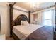 A luxurious main bedroom featuring a four-poster bed, elegant chandelier, and ample natural light at 12275 Styron Dr, Hampton, GA 30228