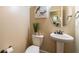 Stylish powder room with pedestal sink, toilet, and decorative mirror at 12275 Styron Dr, Hampton, GA 30228