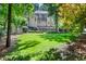 Exterior of home with a large backyard, lush landscaping, and partial brick facade at 5140 Long Island Nw Dr, Sandy Springs, GA 30327