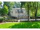 Exterior of home with a private backyard, lush landscaping, a stone chimney and black metal fence at 5140 Long Island Nw Dr, Sandy Springs, GA 30327