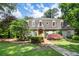 Front exterior of home with green lawn, mature trees, lush landscaping, and stone walkway at 5140 Long Island Nw Dr, Sandy Springs, GA 30327