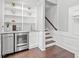 Wet bar with stainless steel beverage cooler, sink, and shelves near staircase at 10300 Carleigh Ln, Roswell, GA 30076