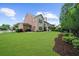 View of a large manicured backyard with a well-maintained lawn and a two-story brick and siding home at 4435 Manor Creek Dr, Cumming, GA 30040
