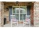 Charming front porch with stone columns featuring two white rocking chairs and striped pillows at 4435 Manor Creek Dr, Cumming, GA 30040