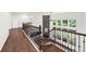 Open hallway with hardwood floors, wrought iron railing, stone fireplace, and large windows with backyard view at 4435 Manor Creek Dr, Cumming, GA 30040