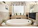 Bright bathroom featuring a soaking tub with tile surround and frosted window at 6861 Louis Dr, Locust Grove, GA 30248