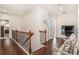 Bright hallway with hardwood floors, wood railing, and a cozy sitting area at 6861 Louis Dr, Locust Grove, GA 30248