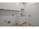 Well-lit laundry room with white cabinets, sink, black faucet, and beautiful light brown brick floor at 863 N Bay Overlook, Villa Rica, GA 30180